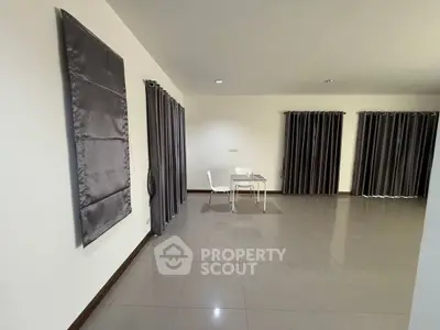 Spacious minimalist living room with sleek tile flooring and modern curtains