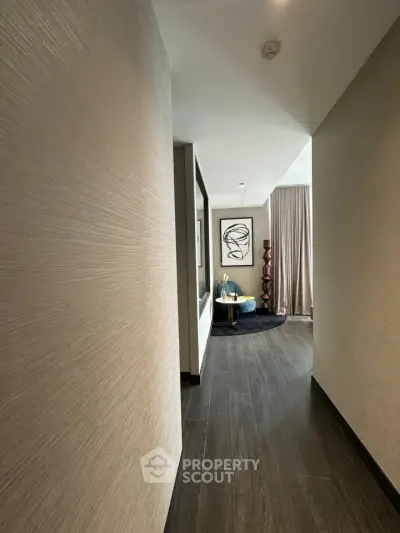 Elegant hallway leading to a stylish living area with modern decor and artwork.