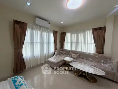 Elegant living room with plush sofa and chic coffee table, featuring large windows and stylish curtains.