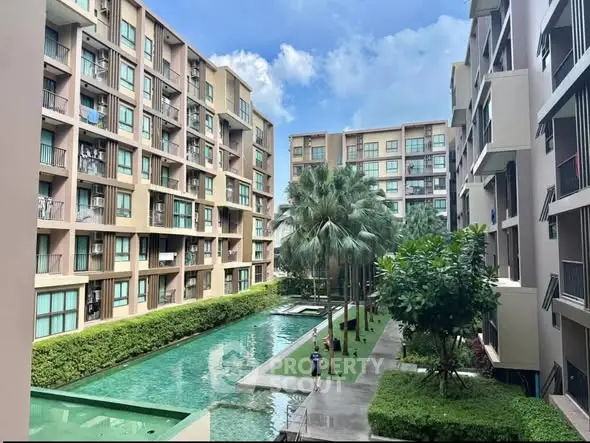 Modern apartment complex with lush greenery and swimming pool view.