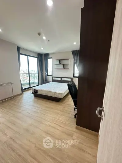 Spacious bedroom with modern furnishings and large windows offering city views.