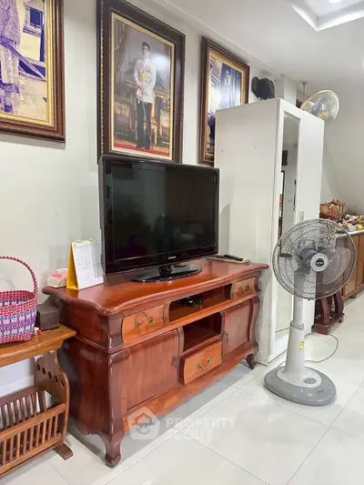 Charming living room with classic wooden furniture and modern TV setup.