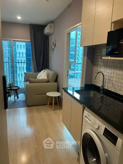Modern apartment interior with cozy living room and compact kitchen featuring washing machine, ideal urban living.