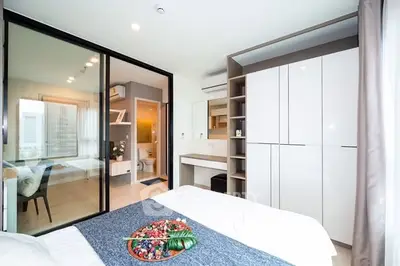Modern bedroom with sleek wardrobe and ensuite bathroom in stylish apartment.