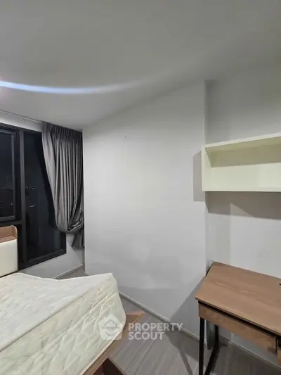 Modern bedroom with minimalist design, featuring a bed, desk, and wall shelf, perfect for urban living.