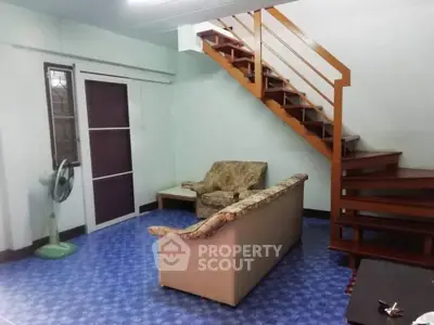 Cozy living room with staircase and vintage furniture, ideal for comfortable living.