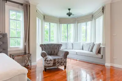 Elegant living room with large windows and stylish furniture, featuring a cozy armchair and a plush sofa.