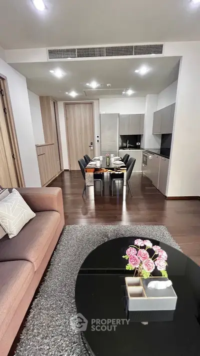 Modern open-plan living room with sleek kitchen and dining area, featuring stylish decor and cozy ambiance.