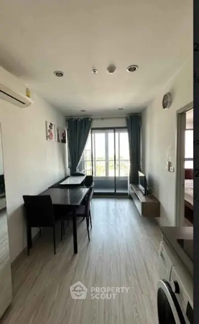Modern living room with dining area and balcony access, featuring sleek furniture and bright natural light.