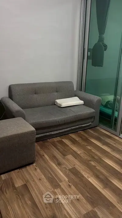 Modern living room with sleek gray sofa and wooden flooring, perfect for cozy relaxation.