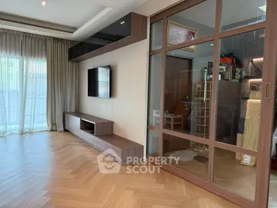 Spacious modern living room with sleek wooden flooring and large windows.