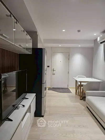 Modern living room with sleek furniture and open layout, featuring a TV and dining area.