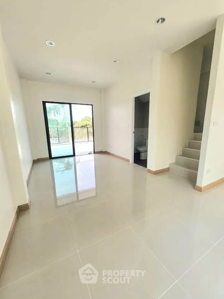 Spacious modern living room with large windows and staircase, perfect for natural light lovers.