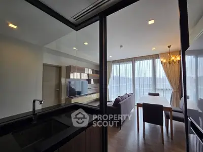 Modern open-layout living room with dining area and large windows offering natural light.