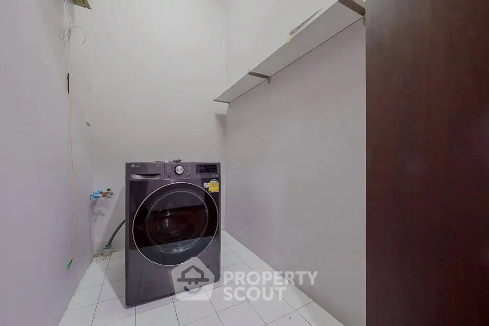 Spacious laundry room with modern washing machine and shelving, perfect for efficient home organization.