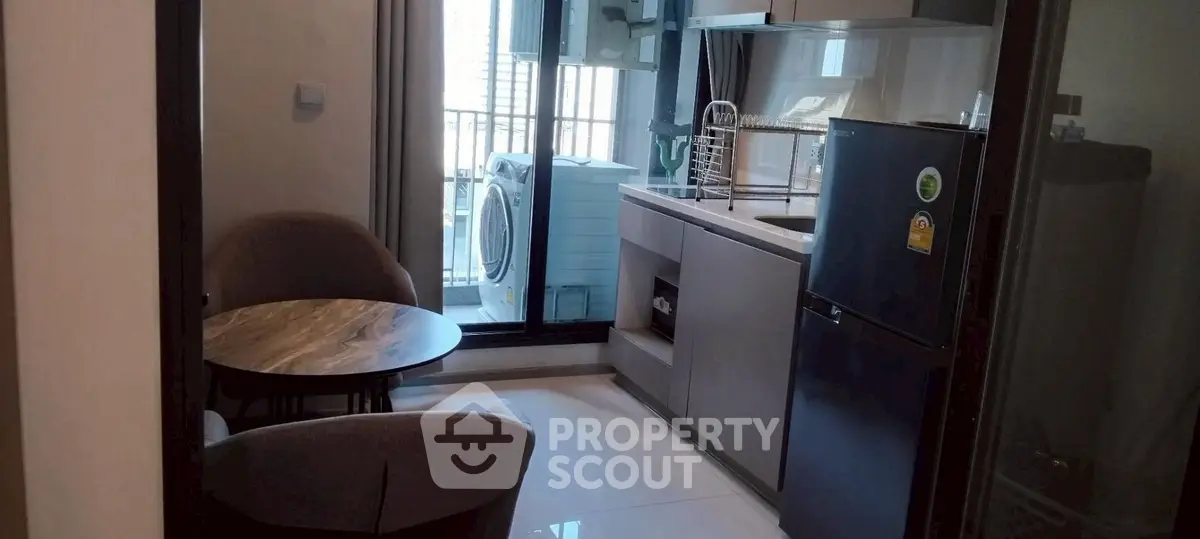 Modern kitchen with balcony view and washing machine in compact apartment