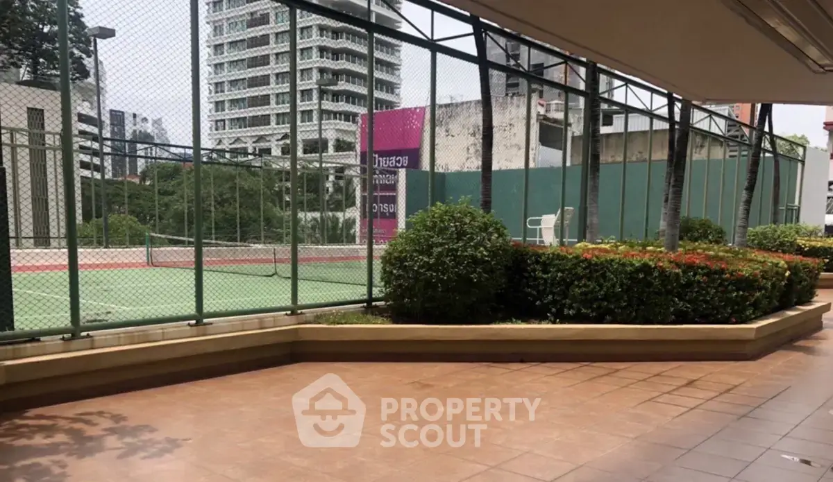 Spacious outdoor tennis court with lush greenery in a modern residential complex.