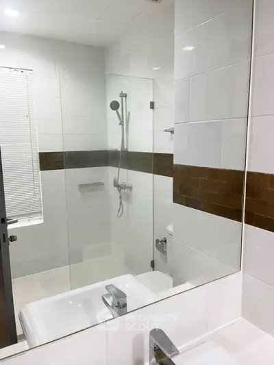 Modern bathroom with glass shower and sleek fixtures in contemporary home.