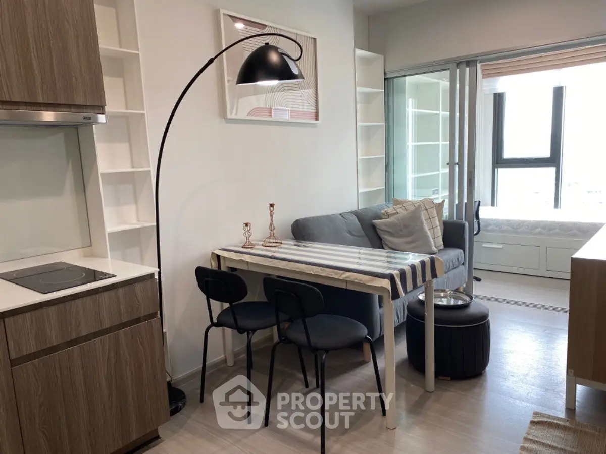 Modern living room with cozy sofa, dining table, and stylish floor lamp in a compact apartment.
