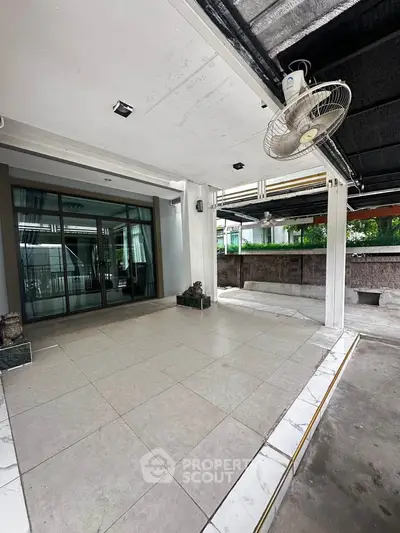 Spacious covered patio with ceiling fan and sliding glass doors, perfect for outdoor relaxation.