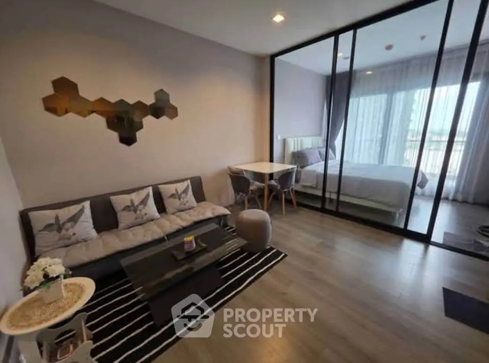 Modern open-plan living room with stylish decor and glass partition to bedroom