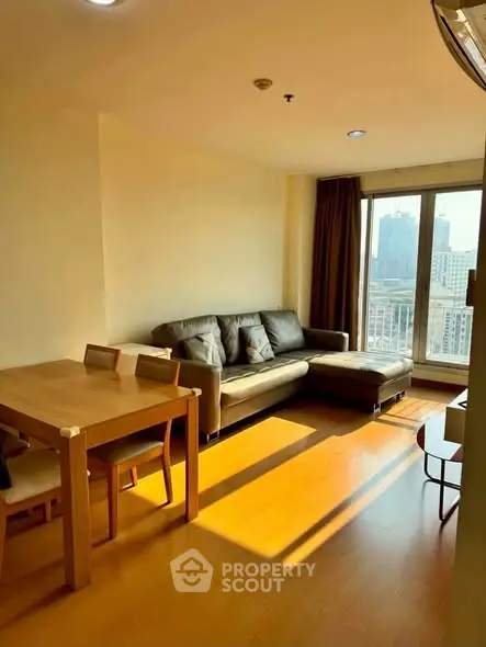 Bright living room with city view, featuring a cozy sofa and dining area, perfect for urban living.