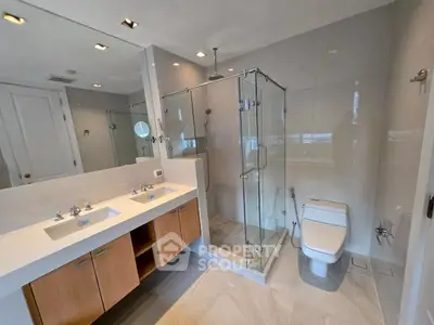 Modern bathroom with glass shower and dual sinks in a sleek design.