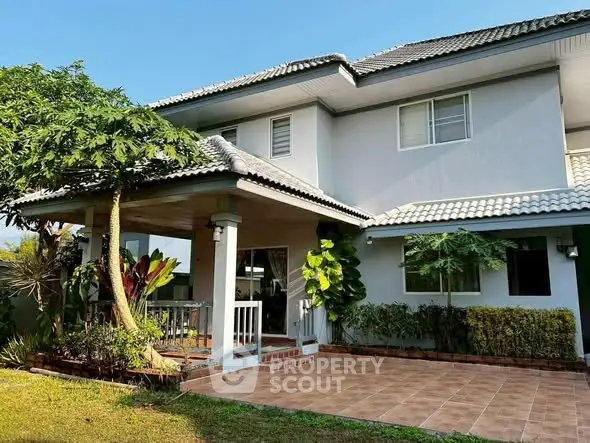 Charming two-story house with tiled patio and lush garden, perfect for family living.