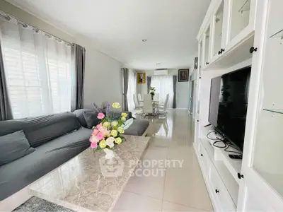 Spacious living room with elegant decor and natural light, featuring a cozy seating area and modern entertainment unit.