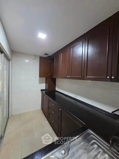 Spacious kitchen with dark wood cabinets and sleek countertops, perfect for culinary enthusiasts.