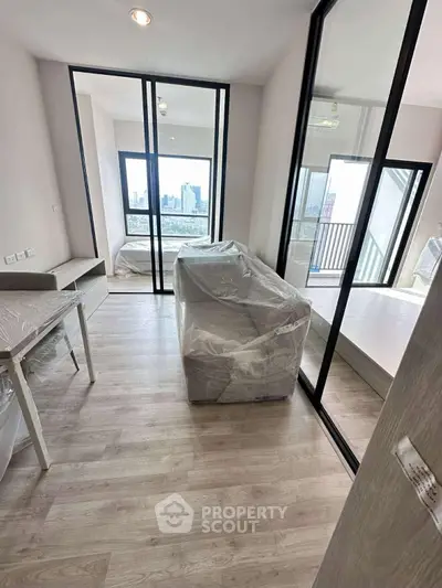 Modern apartment interior with large windows and city view, featuring a cozy living area and bedroom.