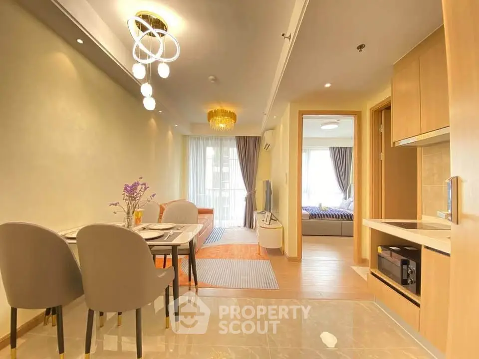 Modern open-plan living and dining area with elegant lighting and cozy bedroom view.