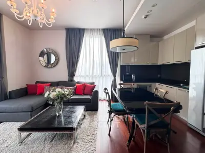 Elegant living room with modern kitchen, stylish chandelier, and cozy seating area.