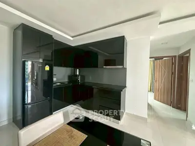 Modern kitchen with sleek black cabinets and dining area in contemporary apartment.