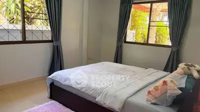 Cozy bedroom with large windows and natural light, perfect for relaxation and comfort.