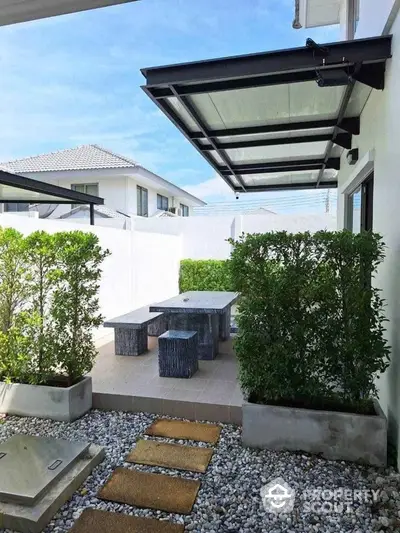 Charming outdoor patio with modern seating and lush greenery in a serene residential setting.