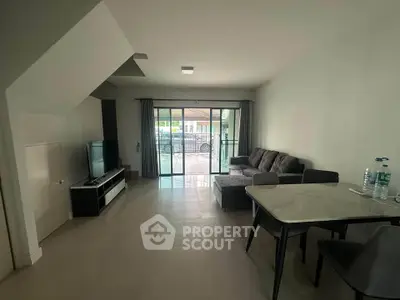 Modern living room with sleek furniture and large glass doors leading to a patio.