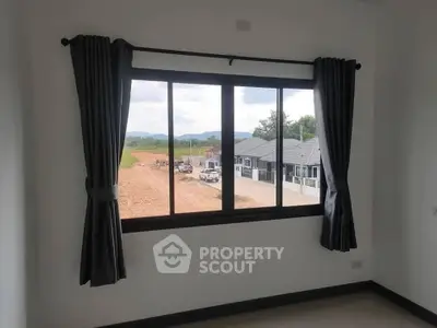 Bright room with large window offering scenic view of developing neighborhood.