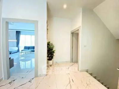 Modern interior hallway with marble flooring and view into a spacious living room.