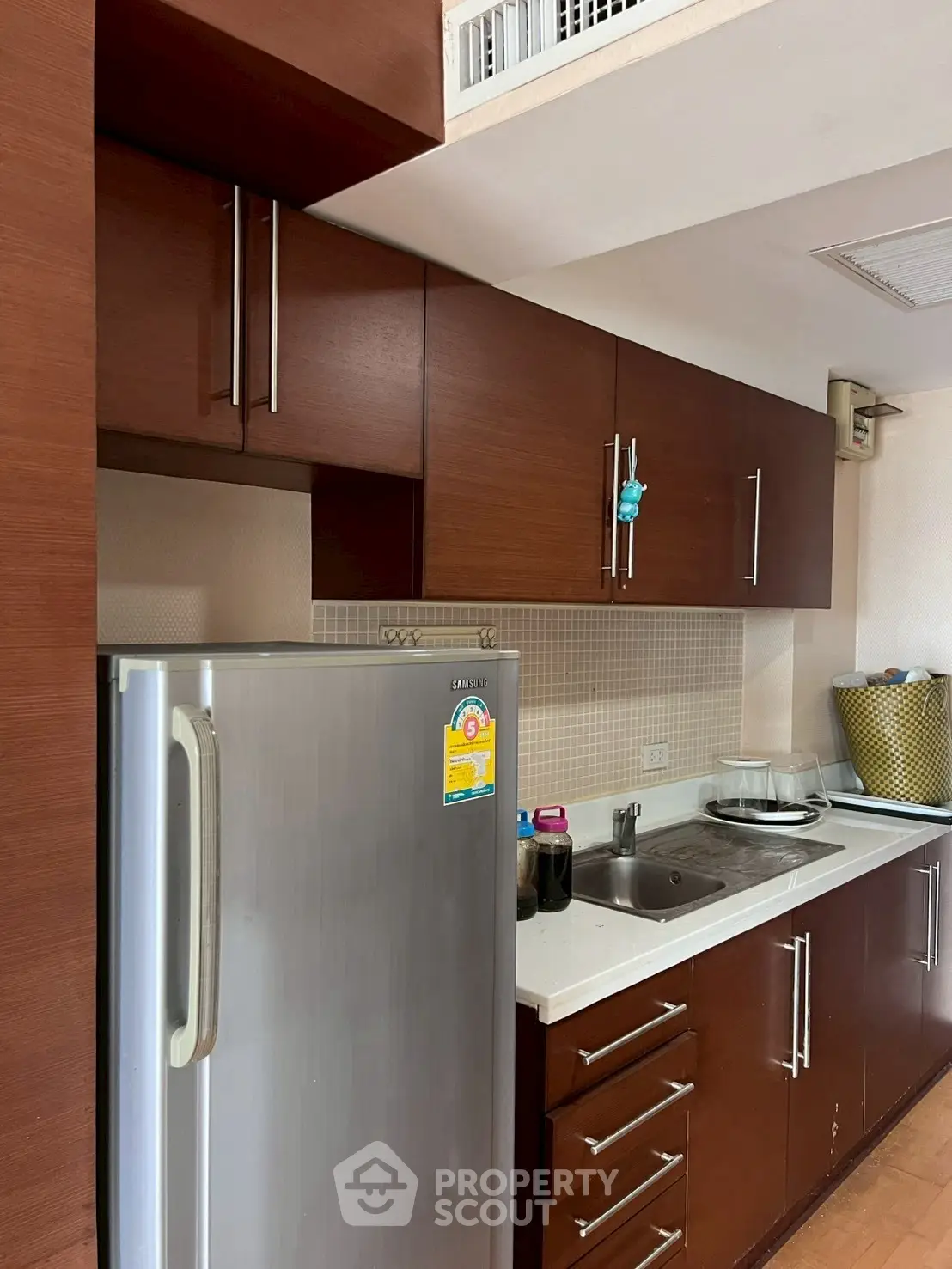 Modern kitchen with sleek cabinetry and stainless steel fridge in cozy apartment.