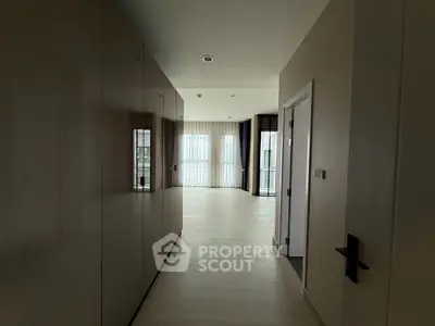 Spacious hallway leading to a bright living area with large windows and modern design.