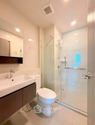 Modern bathroom with glass shower and sleek fixtures in a contemporary apartment.