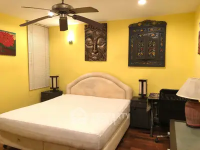 Cozy bedroom with yellow walls, ceiling fan, and artistic decor for a warm ambiance.