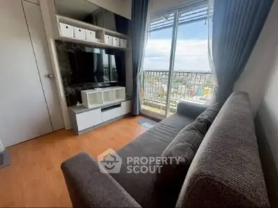 Modern living room with large window and city view, featuring cozy sofa and entertainment unit.
