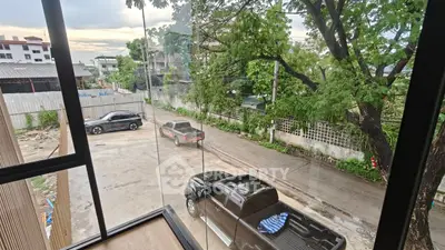 Scenic view from a modern building window overlooking a quiet street with parked cars.