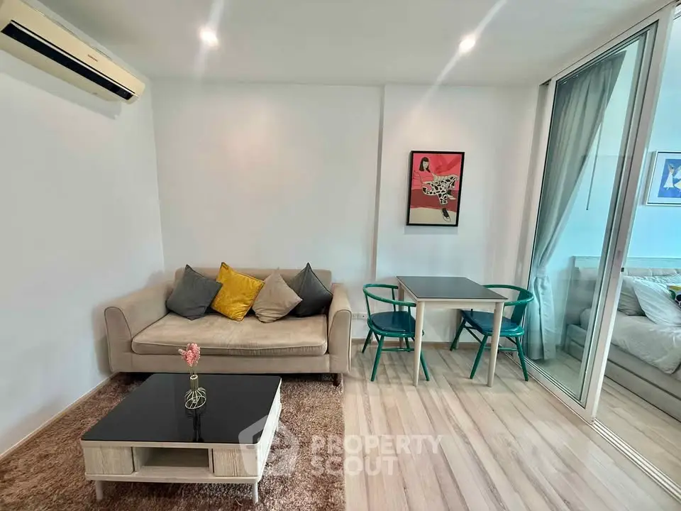 Modern living room with cozy sofa, stylish decor, and glass partition leading to bedroom.