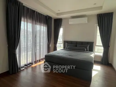 Spacious bedroom with large windows and modern decor, featuring elegant curtains and a comfortable bed.