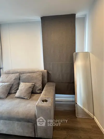 Modern living room with stylish gray sofa and sleek floor mirror, perfect for contemporary urban living.