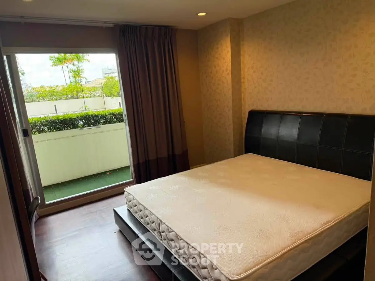 Cozy bedroom with a large window opening to a lush garden view, featuring a comfortable bed and elegant decor.