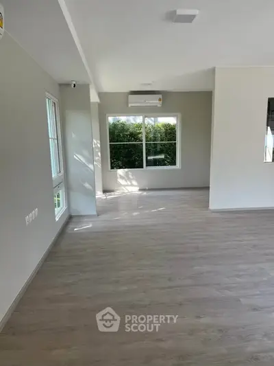 Spacious and bright living room with large windows and modern flooring, perfect for family gatherings.